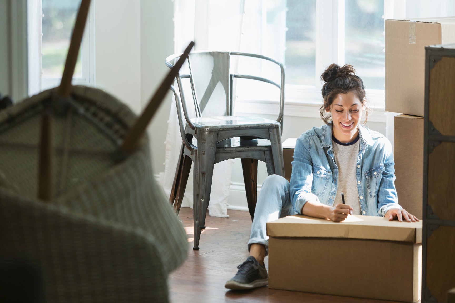 Young mixed race woman moving, writing checklist